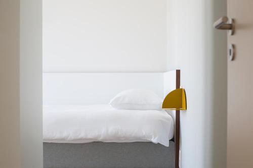 a bedroom with a white bed and a yellow lamp at Cadix 35 in Antwerp