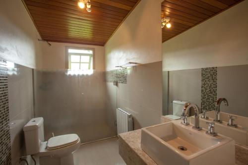 a bathroom with a sink and a toilet and a mirror at Casa Blauth in Farroupilha