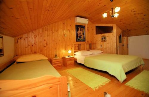 two beds in a room with wooden walls at Haus Randelj in Labin