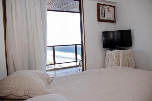 1 dormitorio con 1 cama, TV y ventana en Apartamento Varandas Barra Flat, en Río de Janeiro