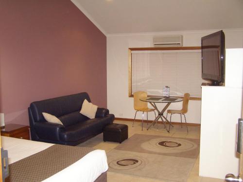 a living room filled with furniture and a tv at Koala Tree Motel in Port Macquarie