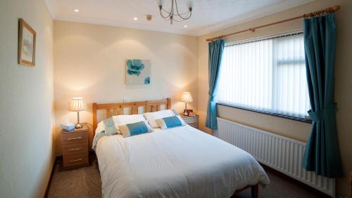 a bedroom with a bed and a window with blue curtains at Browns Country House in Bushmills