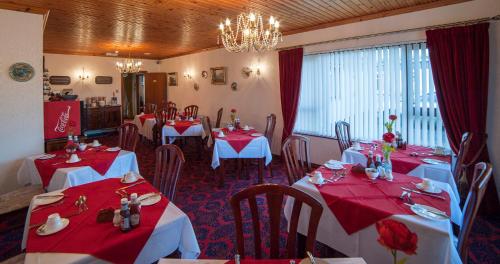 a dining room with red and white tables and chairs at Browns Country House in Bushmills