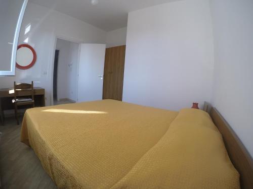 a yellow bed in a room with a desk at Appartamenti Torre in Capo Vaticano