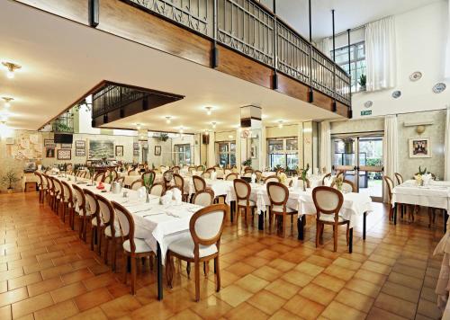 una sala da pranzo con tavoli e sedie bianchi di Hotel Residence Sogno a Novara