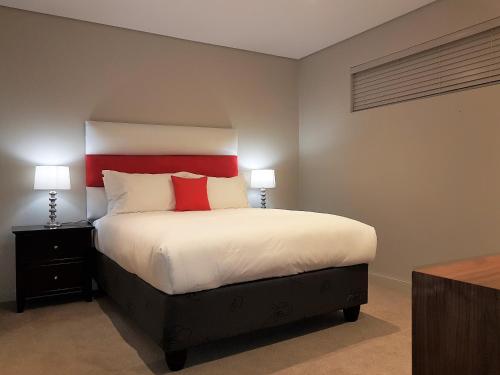 a bedroom with a large bed with red accents at Zimbali Suites 301 in Ballito