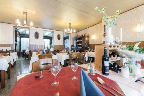 ein Restaurant mit einem Tisch mit Weingläsern darauf in der Unterkunft Hotel DeFive in Berdorf