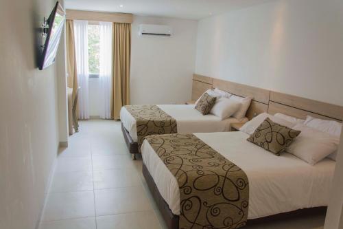 a hotel room with two beds and a television at Hotel Arawak Plaza in Sincelejo