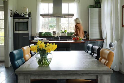 a kitchen with a table with yellow flowers on it at PicaBella - B&B en atelier in Laren