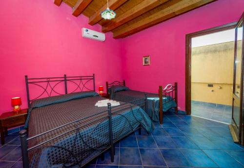 カステッランマーレ・デル・ゴルフォにあるAppartamento Mediterraneoのピンクの壁のベッドルーム1室(ベッド2台付)