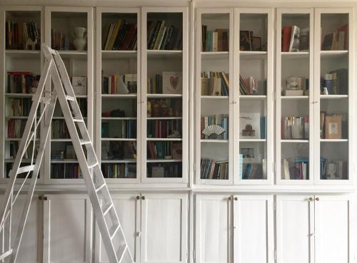 a ladder in front of a white cabinet with books at Villa Pacchioni in Cavezzo