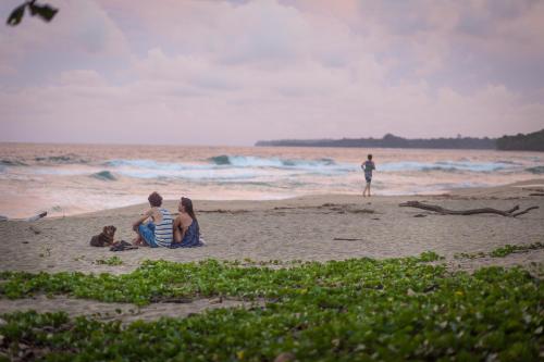 grupa trzech osób siedzących na plaży w obiekcie Playa 506 Beachfront Hostel w mieście Puerto Viejo