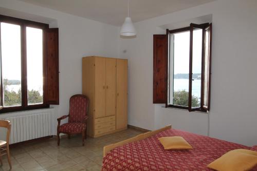 a bedroom with a bed and a chair and windows at Hotel La Marinella in Castiglioncello