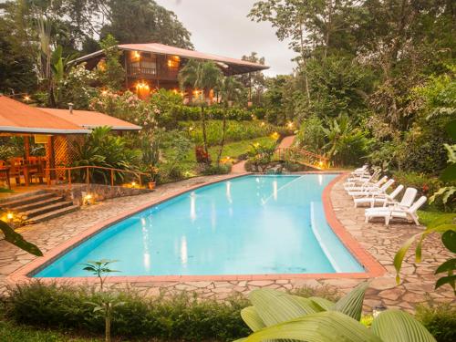 a swimming pool with lounge chairs and a house at Finca Luna Nueva Lodge in Fortuna
