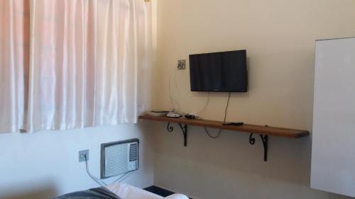 a room with a flat screen tv on a wall at Falcon Hotel in Bauru