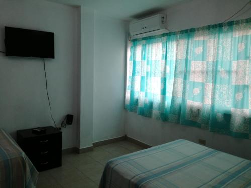 a bedroom with a bed and a television and a window at Francisco Habitaciones in Manta