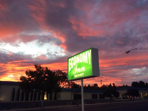 a sign in front of a building with a sunset at Economy Inn Paso Robles in Paso Robles