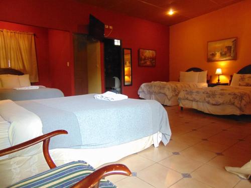 a hotel room with two beds with red walls at Managua Hills in Managua