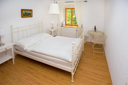 a bedroom with a white bed and a desk and a window at Weingut Mariaberg in Meißen