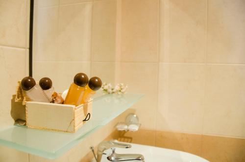 a bathroom with a sink and a shelf with a toothbrush at Family Hotel Dinchova kushta in Rozhen