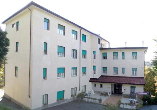 a large white building with green windows at Albergo Villa Margherita in Tiglieto