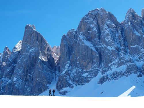 two people skiing in front of a snowy mountain at Hotel Tyrol in Funes
