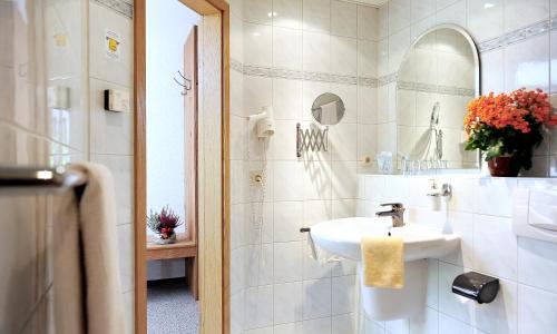 a white bathroom with a sink and a mirror at Kelten-Hotel in Sünna