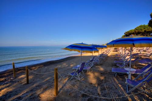 Villaggio Il Girasole في فولونيكا: مجموعة من الكراسي والمظلات على الشاطئ
