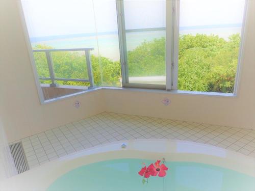 a bathroom with a bath tub with a window at Seaside KLATCH -Villa&sauna- in Ishigaki Island