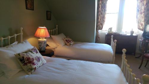 two beds in a bedroom with a lamp and a lamp at Lochinver Guesthouse in Ayr