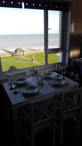 a table with wine glasses and a view of the beach at Seabreeze in Littlestone-on-Sea