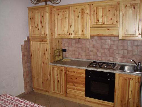 a kitchen with wooden cabinets and a stove top oven at Appartamento Lanner in Sappada