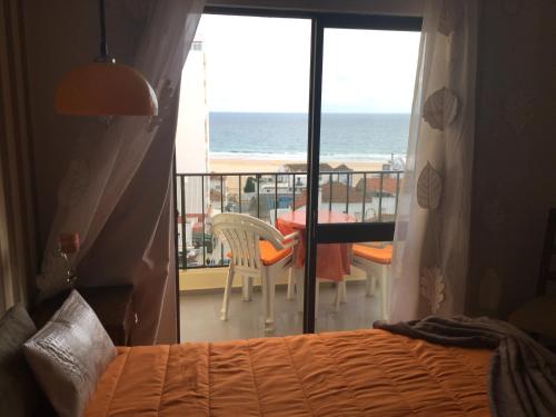 a bedroom with a balcony with a view of the ocean at Apartamento Cruzeiro Praia da Rocha in Portimão