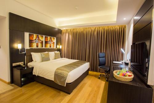 Habitación de hotel con cama, escritorio y TV. en Golden Tulip The Grandmark Dhaka en Dhaka