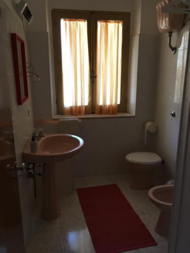 a bathroom with a sink and a toilet and a window at Anna Apartment in Villaputzu