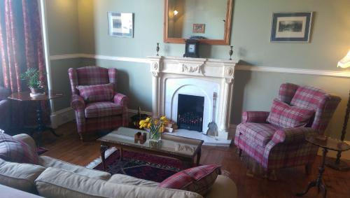 a living room with two chairs and a fireplace at Lochinver Guesthouse in Ayr