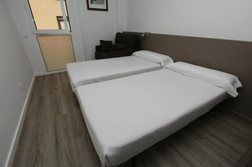 a bedroom with two beds and a chair at Hotel Alguer Camp Nou in Barcelona