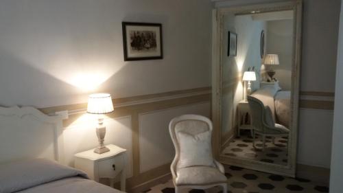 een slaapkamer met een spiegel, een bed en een stoel bij Luxury apartment Suite La Fontana in Lucca