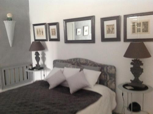 a bedroom with a bed with four pictures on the wall at Maison d'Hôtes Mas de Barbut in Saint-Laurent-dʼAigouze