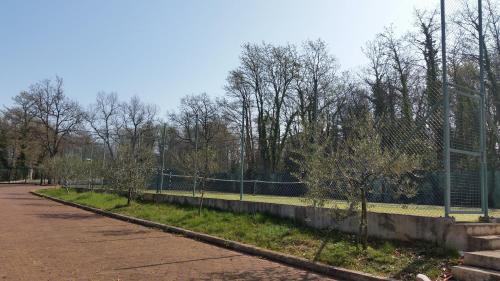 a fence next to a road with trees behind it at Hotel Zlatna Vala in Umag