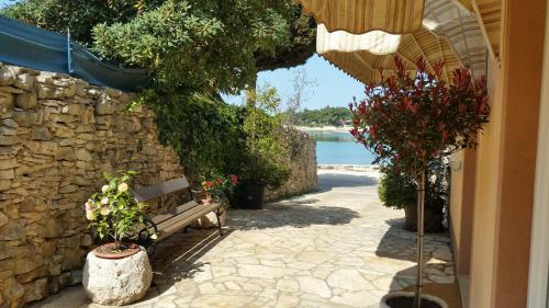 a bench sitting next to a stone wall with plants at Hotel Zlatna Vala in Umag