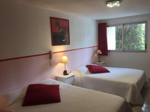 a hotel room with two beds and a window at Lou Garbin in Saint-Laurent-dʼAigouze