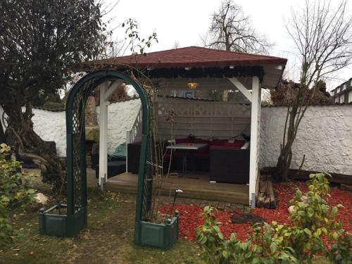 a gazebo with a table in a garden at Am Hallenbad Hotel garni in Ratingen