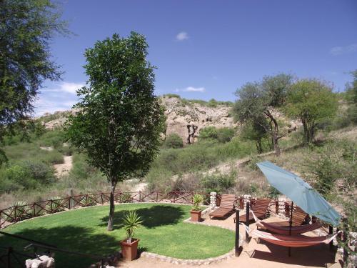 a table and chairs with an umbrella in a garden at Sasa Safari Camp & Tours in Outjo
