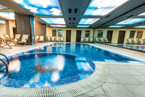 a large swimming pool with blue water in a building at Gardenia Park Hotel in Bansko