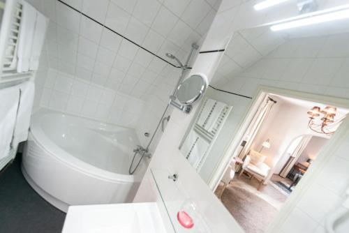 a bathroom with a tub and a toilet and a sink at Charmehotel Klokkenhof in Brasschaat