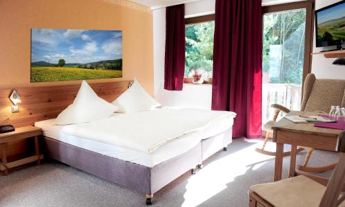 a bedroom with a bed and a desk and window at Kelten-Hotel in Sünna