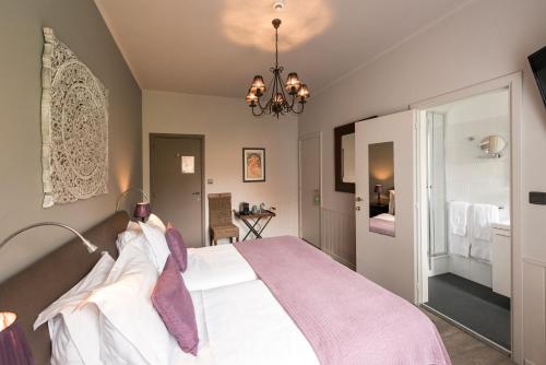 a bedroom with a large bed and a chandelier at Charmehotel Klokkenhof in Brasschaat