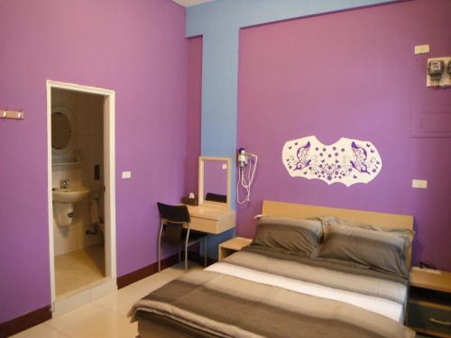 1 dormitorio con paredes moradas, 1 cama y lavamanos en The Beauty of Basalt B&B, en Magong