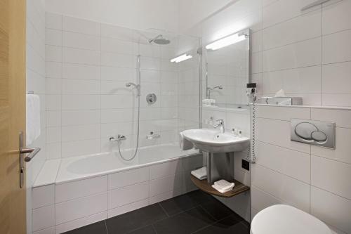a white bathroom with a sink and a shower at Hotel Phoenix in Zermatt